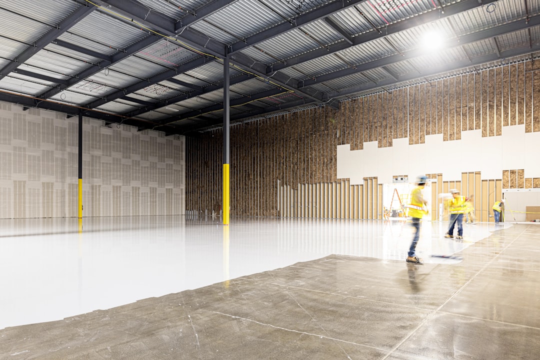 Two construction workers in a large empty warehouse
