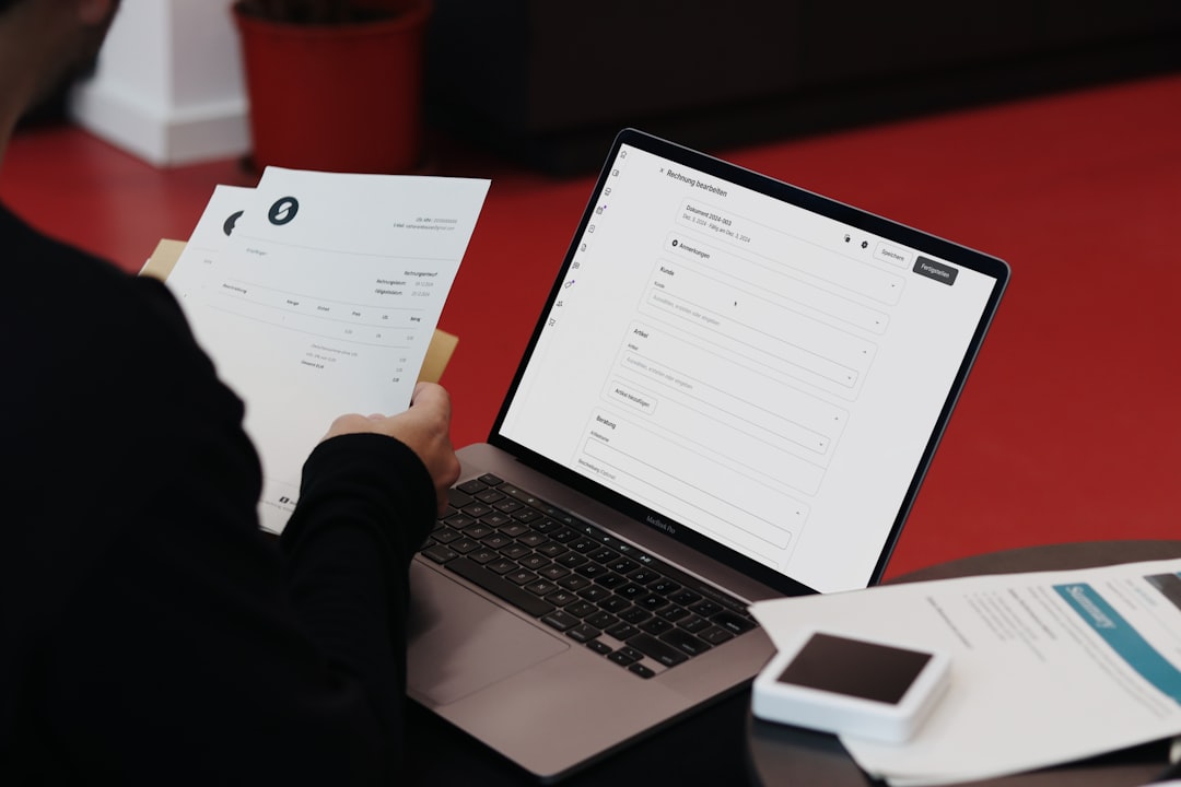 Przedsiębiorca pracujący z fakturami na laptopie